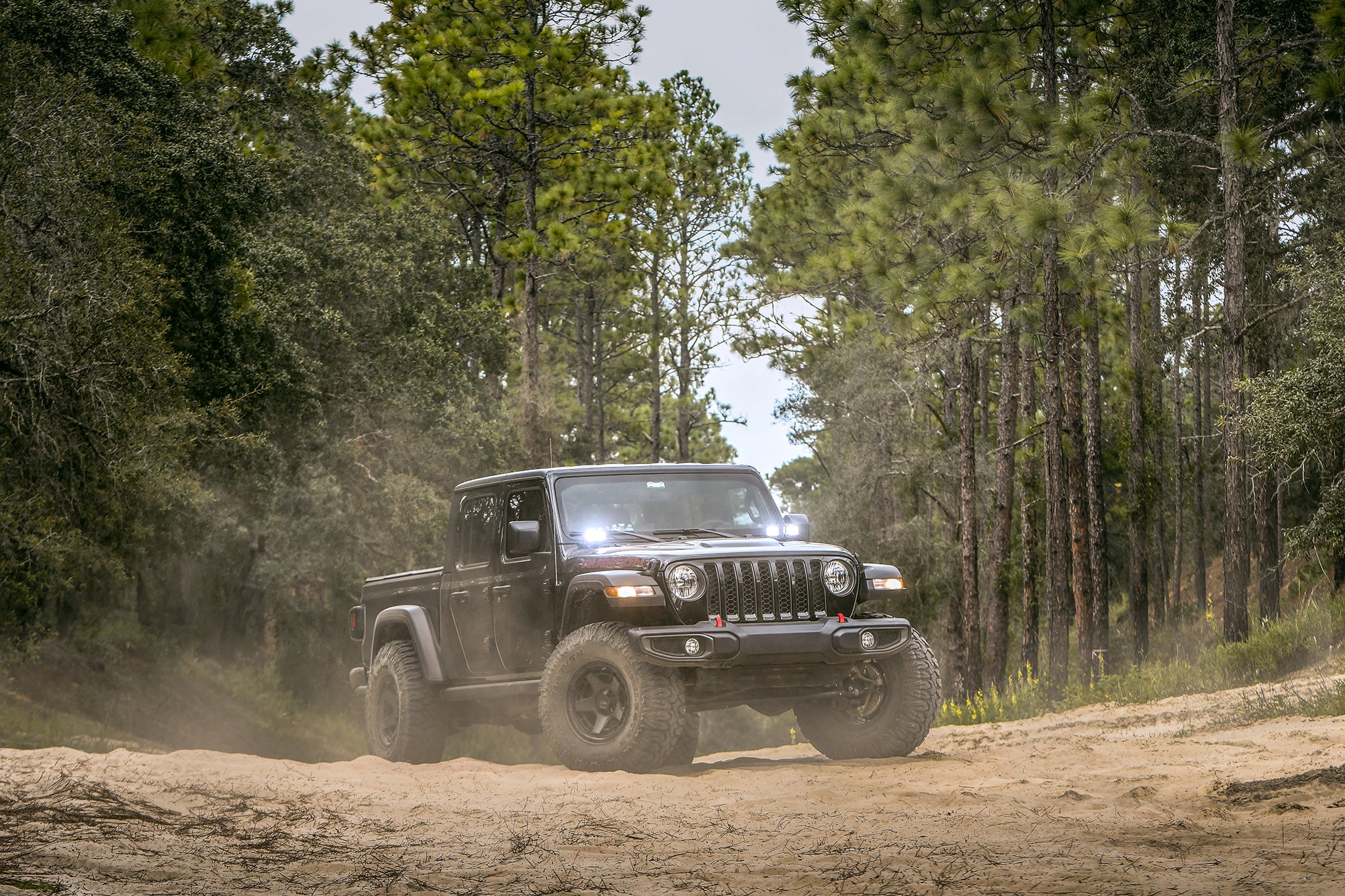 overland sector wheels jeep gladiator rubicon on 17x9 satin black atlas wheels in woods on dirt trail